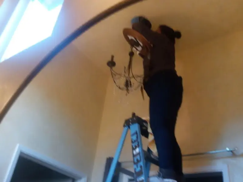 Electrician installing a chandelier in a Pine Level residence